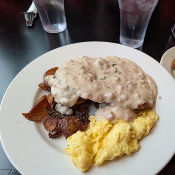 A plate of biscuits and gravy with scrambled eggs and roasted potatoes at Wild Duck Cafe.