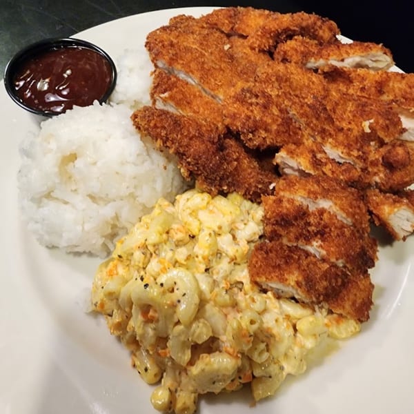 Crispy fried chicken cutlets, white rice, macaroni salad, and a side of barbecue sauce on a plate.